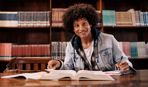 Young confident student studying in library
