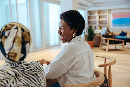 Coworkers laughing together in a modern office space enjoying a relaxed conversation