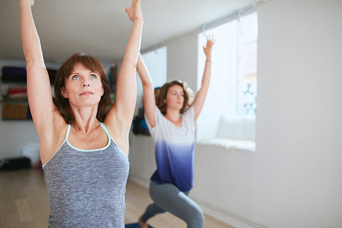 Two women practicing yoga forms at class