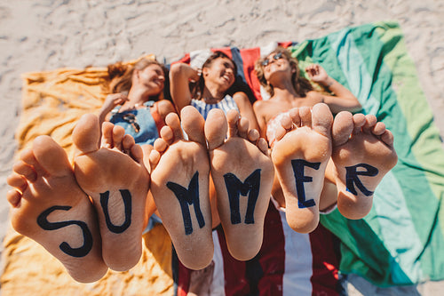 Bare feet of female friends with word summer