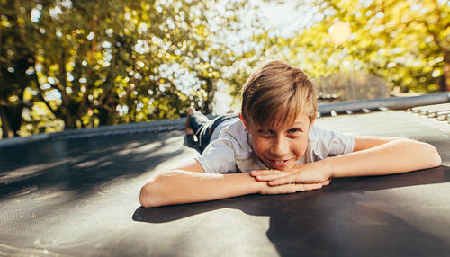 Little boy resting on trampoline after playing
