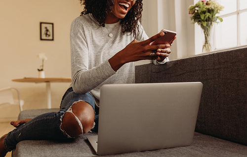 Woman managing business from home with mobile phone and laptop