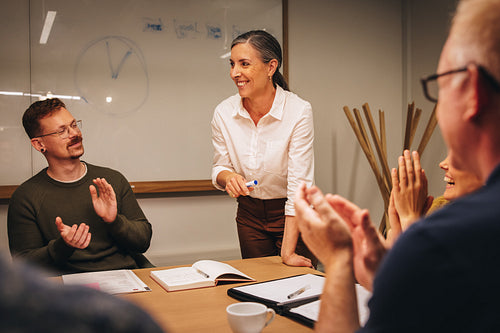 Businesswoman getting applause in team meeting