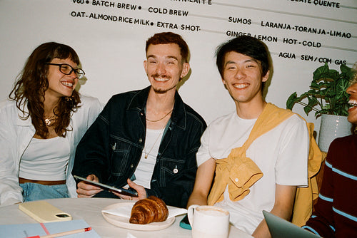 Young entrepreneurs laughing over coffee and planning a project