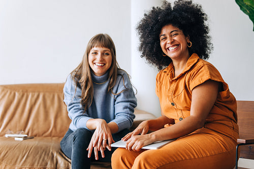 Two successful businesswomen smiling at the camera in a lobby