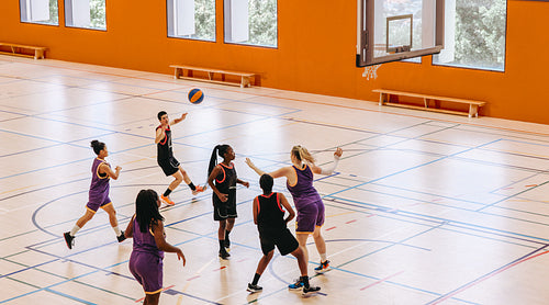 Female basketball players playing an intensive game in a dynamic indoor court