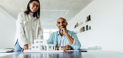 Two young architects working on a house model in an office