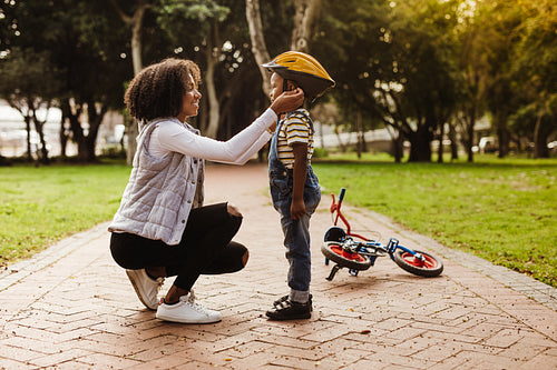 Mother puts her son protective helmet for riding bike