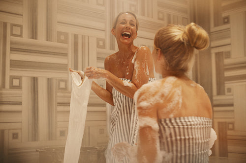 Two women laughing and having fun in a hammam spa