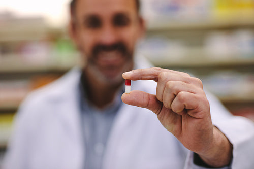 Male pharmacist holding a pill