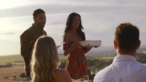 Couple serving food to friends