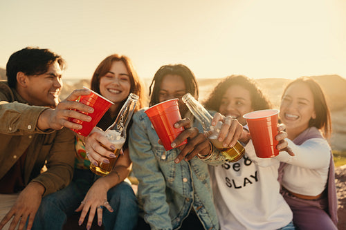 Group of friends cheering and drinking with happiness outdoors