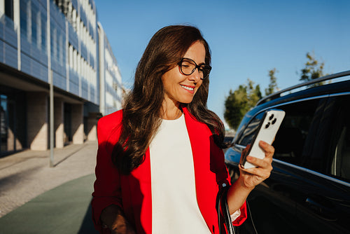 Professional woman using a smartphone outside an office building in daylight