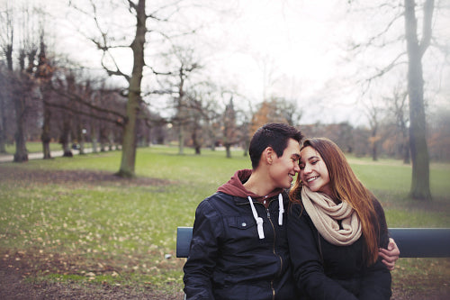 Romantic young couple sitting on a park bench 