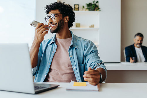 Successful young entrepreneur using a laptop and smartphone at a modern office