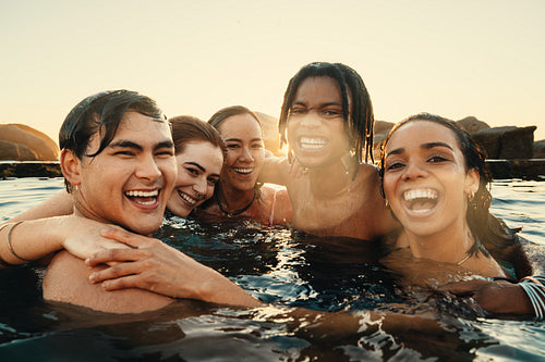 Best friends enjoying a fun day abroad in a swimming pool at sunset