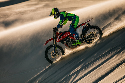Professional motocross biker riding in sand dunes