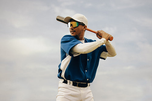 Focused baseball player preparing to swing under a clear sky during practice