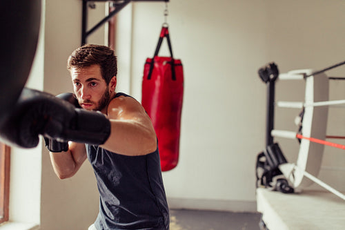 Young boxer striking punching bag in a gym