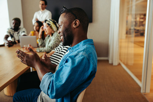 Businessman applauding in a casual meeting setting in a diverse office environment