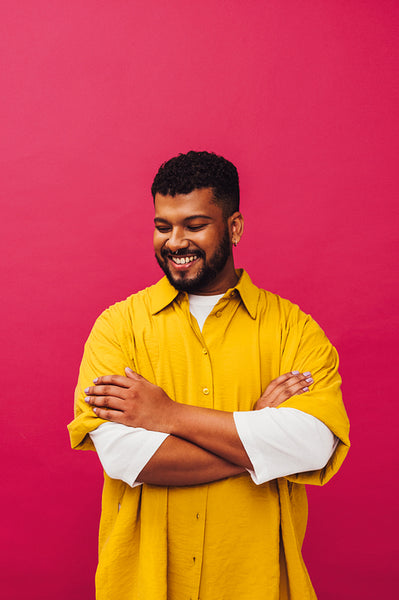 Young man smiling against a pink background