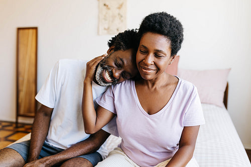 Affectionate wife hugging and cuddling her husband on their bed bed, happy and in love