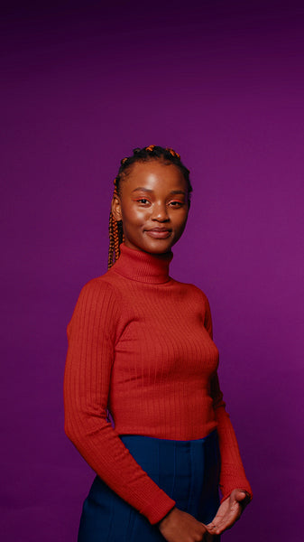 Young woman standing confidently against a vibrant purple backdrop