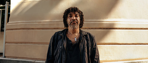 Self-confident homeless man looking at the camera outdoors