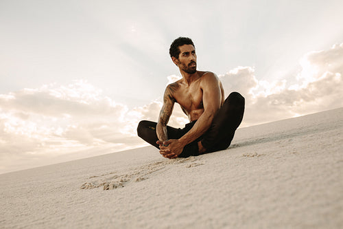 Athlete doing stretches on sand dunes