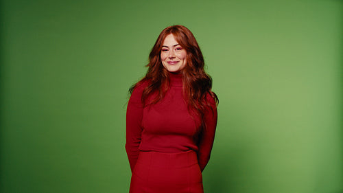 Happy woman in red smiling, winking, and laughing on green screen