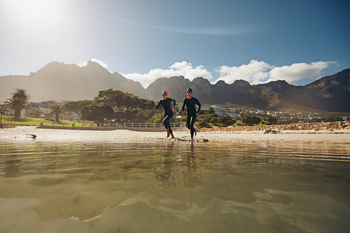 Two triathletes running into the water
