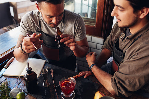 Two bartenders experimenting with creating cocktails