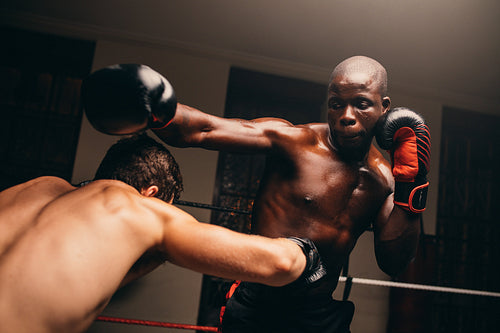 Two male fighters having a match in a boxing ring