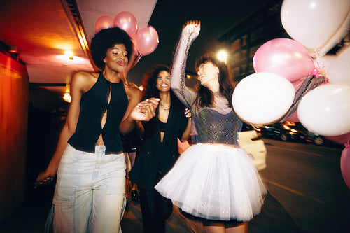 Group of friends celebrating outdoors during nighttime party with balloons and joy