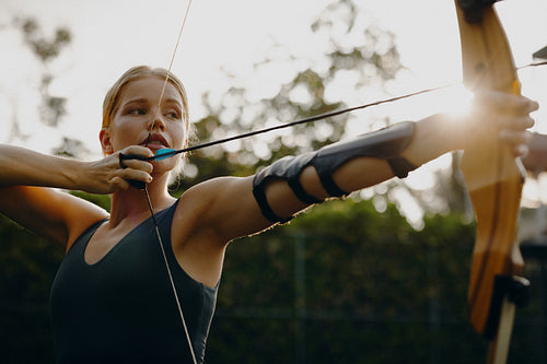 Focused female archer practicing outdoors