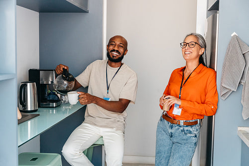 Co-workers enjoying a coffee break in office kitchen
