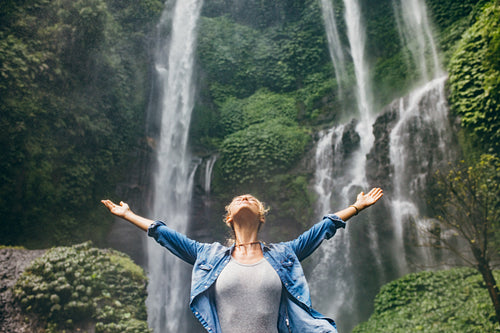Young woman standing in front of waterfall
