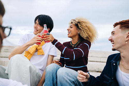 Friends laughing and toasting with soda in candid moment