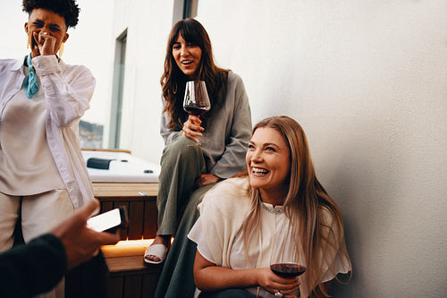 Friends laughing and enjoying wine together on a cozy outdoor patio