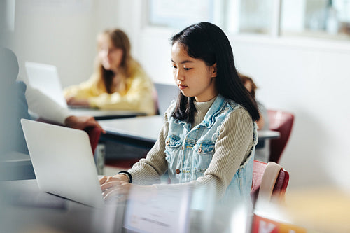 The next big coder: Young girl sits in a coding class, working on a task using her laptop