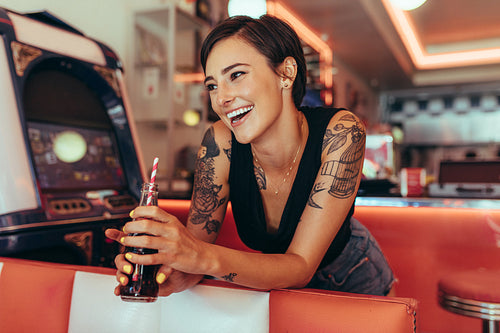 Woman standing beside a gaming machine at a diner holding a soft drink