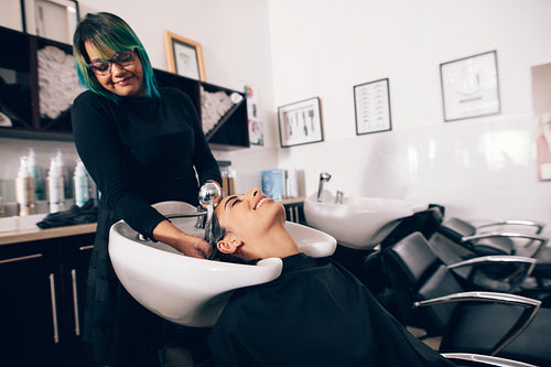 Hairdresser washing hair of customer at salon