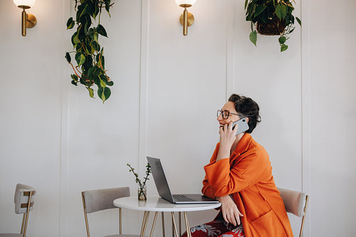 Successful business woman speaking on a phone call while working in a cafe