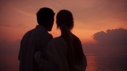 Couple embraces at peaceful sunset over the ocean