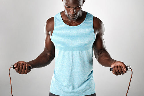 Muscular young man exercising with jumping rope