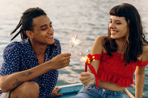 Carefree young couple celebrating with Bengal lights on a vacati