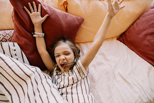 Playful moment: girl joyful on bed with pillows