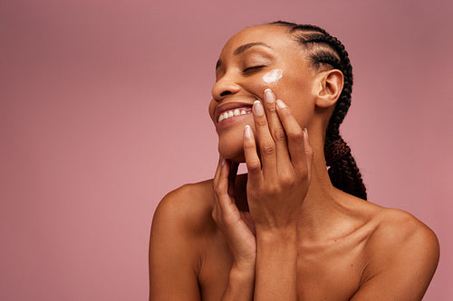Woman applying face cream and smiling