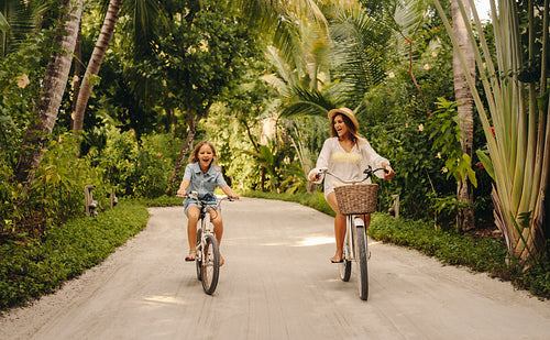 Happy family biking on a lush tropical island during vacation