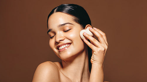 Skincare with a beauty blender; woman applies a facial product on her perfect skin